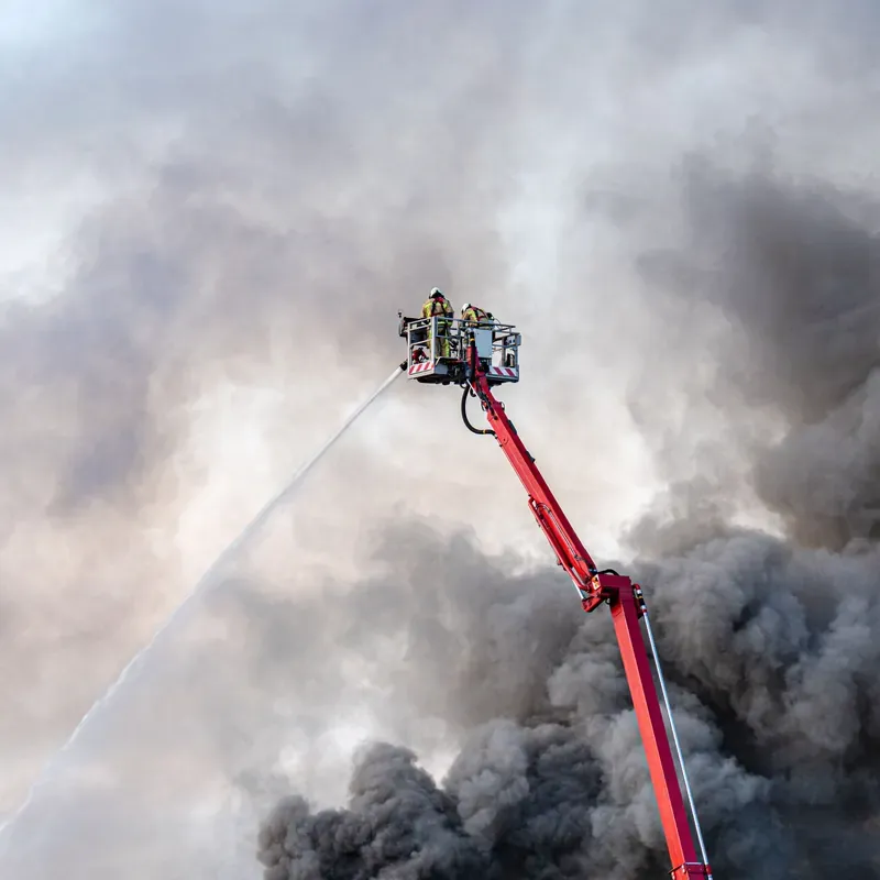 Feuerwehr im Korb eines Teleskopmastes beim Löschangriff aus der Höhe